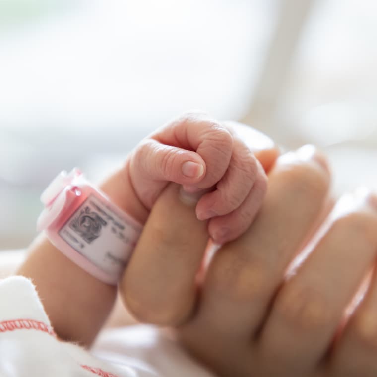 Dłoń noworodka ściskającego palec matki